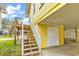 Ground level view showcases stairs leading to an elevated beach house and storage area at 121 Easy St., Garden City Beach, SC 29576