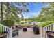 Backyard patio with seating, a fire pit, and a grill, overlooking a serene pond and lush greenery at 179 Cottage Ct., Pawleys Island, SC 29585