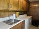 A laundry room features a stainless steel sink, neutral countertop, wooden cabinets, and a white washing machine at 189 Lewis Rd., Hemingway, SC 29554