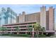 Multi-story exterior of condo with parking garage and palm trees offers beach access at 2207 S Ocean Blvd. # 718, Myrtle Beach, SC 29577
