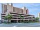 Exterior of a multi-story beach condo with a parking garage and lush landscaping at 2207 S Ocean Blvd. # 718, Myrtle Beach, SC 29577