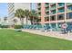 Poolside lounge chairs offer a relaxing space next to lush palms and stunning building views at 2207 S Ocean Blvd. # 718, Myrtle Beach, SC 29577