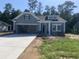 Charming single-story home featuring gray siding, stone accents, an open garage, and manicured landscaping at 260 Palmetto Sand Loop, Conway, SC 29527