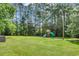 Expansive backyard with lush green grass and mature trees, featuring a play set at 265 Powell Loop, Andrews, SC 29510