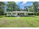 Charming single-story white brick home featuring a well-manicured lawn and cozy front porch with rocking chairs at 265 Powell Loop, Andrews, SC 29510