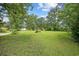 Expansive grassy front yard features mature trees and lush greenery creating a serene and inviting outdoor space at 300 Crescent Dr., Conway, SC 29526