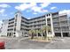 Exterior view of condo building with balconies, palm trees, and parking area at 305 Hillside Dr. N # 205, North Myrtle Beach, SC 29582