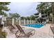 A refreshing community pool is surrounded by lounge chairs, a wooden fence, and mature trees providing a serene oasis at 404 72Nd Ave. N # 301, Myrtle Beach, SC 29572