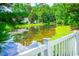 Serene pond view from a backyard with a white picket fence, highlighting the tranquil setting at 4499 Firethorne Dr., Murrells Inlet, SC 29576