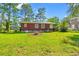 A spacious backyard featuring a lush green lawn and mature trees, offering a private outdoor space at 506 28Th Ave. N, Myrtle Beach, SC 29577