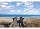 Inviting wooden boardwalk leading to a sandy beach and the ocean under a bright, partly cloudy sky at 611 N Ocean Blvd., Surfside Beach, SC 29575