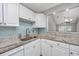 Kitchen with granite countertops, stainless steel faucet, blue backsplash, and white cabinets at 612 Intracoastal Way Dr. # 103, Myrtle Beach, SC 29579