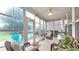 Relaxing sunroom featuring tiled floors, ceiling fan, large windows providing stunning backyard views, and comfortable wicker furniture at 698 Lafayette Park Dr., Little River, SC 29566