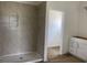 Walk-in shower features tiled walls, a shower head, and inset shelving, next to a door at 982 Oak Hollow St., Longs, SC 29568