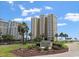 A beautiful view of the exterior of Arcadian I & II resort with well-maintained landscaping and a bright blue, cloudy sky at 10200 Beach Club Dr. # 16F, Myrtle Beach, SC 29572