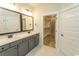 Well-lit bathroom with double vanity and stone counters located next to walk-in closet with shelving at 1514 Saw Palmetto St., North Myrtle Beach, SC 29582