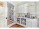 Well-organized laundry room with storage cabinets, marble countertops, and sink with shelving and laundry accessories at 155 Preservation Circle, Pawleys Island, SC 29585
