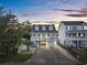 Inviting two-story home with a covered porch, lush landscaping, and an illuminated driveway at dusk at 1725 26Th Ave N, North Myrtle Beach, SC 29582