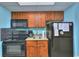 Compact kitchenette with dark wood cabinets, black appliances, and a granite-style countertop at 2000 N Ocean Blvd. # 1209, Myrtle Beach, SC 29577