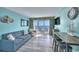 Bright living room with blue sofa, balcony access, and ocean view from the table with bar stools at 2000 N Ocean Blvd. # 1209, Myrtle Beach, SC 29577