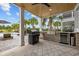 Undercover outdoor kitchen features a brick surround, stainless grill, mini fridge, and a beautiful view to the pool at 496 West Palm Dr., Myrtle Beach, SC 29579