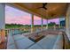Covered porch with outdoor seating, ceiling fans, and a view of a golf course and waterway at sunset at 496 West Palm Dr., Myrtle Beach, SC 29579