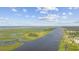 Stunning aerial view of a coastal landscape featuring a wide river, marshland, and waterfront properties under a cloudy sky at 7288 Schooners Ct. Sw, Ocean Isle Beach, NC 28469