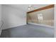Carpeted upstairs room with a ceiling fan, exposed wood beams, and a railing overlooking the lower level at 7288 Schooners Ct. Sw, Ocean Isle Beach, NC 28469