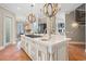 Open kitchen with wooden chandeliers, white island, and chef's range overlooking a nearby dining and ocean view at 100 Ocean Park Loop, Georgetown, SC 29440