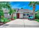 Charming home featuring a vibrant red door, palm trees, manicured landscaping, and a golf cart parked in the driveway at 10056 Kings Rd., Myrtle Beach, SC 29572