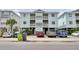 Three-story condo building featuring balconies, light blue siding, and parking underneath the building at 101 W First St. # A2, Ocean Isle Beach, NC 28469