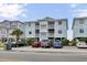 Three-story condo building featuring balconies, light blue siding, and parking underneath the building at 101 W First St. # A2, Ocean Isle Beach, NC 28469