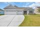 Charming single-story home featuring a three-car garage and manicured lawn under a bright, partly cloudy sky at 1121 Oxeye St., North Myrtle Beach, SC 29582