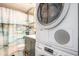 Modern bathroom with stacked washer and dryer, gray vanity, toilet and tiled shower behind curtain at 1205 Erin Way # 5C, Myrtle Beach, SC 29577