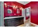 Bathroom with a double sink vanity, stylish fixtures and a bright red wall, featuring a large mirror at 1473 Basin Trail, Murrells Inlet, SC 29576