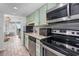 Well-lit kitchen featuring stainless steel appliances, granite countertops, and charming light green cabinetry at 2001 S Ocean Blvd. # 1405, Myrtle Beach, SC 29577