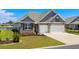 Charming home featuring a brick and siding facade, a two-car garage, and a beautifully landscaped front yard with lush greenery at 215 Kendrick St., Little River, SC 29566