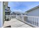 View of a wooden balcony featuring white railings and partial view of adjacent homes under a sunny, blue sky at 421 30Th Ave. S, Sunset Beach, NC 28468