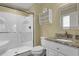 Bathroom featuring white shower, granite sink, and white fixtures, illuminated by warm, natural light at 421 30Th Ave. S, Sunset Beach, NC 28468