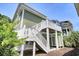 Low angle view of a home's green exterior with a white staircase and an outdoor shower at 421 30Th Ave. S, Sunset Beach, NC 28468
