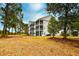 A pristine exterior view of the condo featuring screened in porches in a peaceful wooded setting at 5050 Windsor Green Way # 203, Myrtle Beach, SC 29579