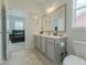Well-lit bathroom showcasing a large mirror, grey vanity, and toilet next to an open door leading to a bedroom at 6186 Chadderton Circle, Myrtle Beach, SC 29579