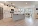 Open floor plan with kitchen island, dining room, white cabinets, stainless steel appliances, and wood-look floors at 6186 Chadderton Circle, Myrtle Beach, SC 29579