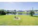 Serene backyard view with lush green grass, a peaceful pond, and neighboring houses in the distance at 708 Shenanigan Loop, Murrells Inlet, SC 29576