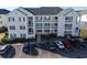 Three-story condo building with white siding and blue shutters surrounded by mature landscaping and parking lot at 901 West Port Dr. # 712, North Myrtle Beach, SC 29582