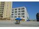 Beachfront condo building with multiple balconies and views, enhanced by beach chairs and a blue umbrella at 920 N Waccamaw Dr. # 2206, Garden City Beach, SC 29576