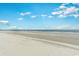 Expansive beach view with a clear blue sky, calm ocean waters, and a wide sandy shoreline at 9400 Shore Dr. # 411, Myrtle Beach, SC 29572