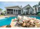 Backyard view of a pristine pool with a waterfall feature and surrounding tropical landscaping at 174 Edward Ave., Murrells Inlet, SC 29576