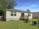 Backyard featuring a small deck, green grass, and outdoor furniture with a wooded horizon at 2021 Loblolly St., Georgetown, SC 29440