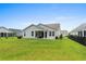 Spacious backyard featuring a well-maintained lawn, a covered patio, and a charming exterior view of the house at 264 Switchgrass Loop, Little River, SC 29566